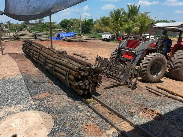 Trator posicionando um feixe de palanques sobre os trilhos da autoclave