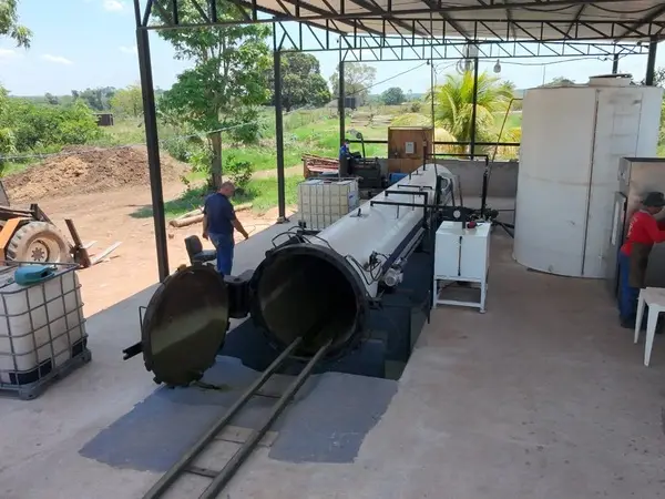 Equipe trabalhando junto à autoclave aberta no galpão de tratamento